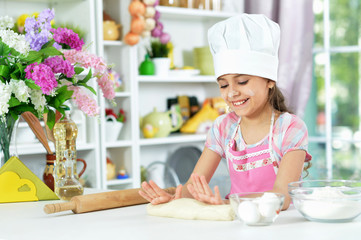 Cute girl making dough in the kitchen