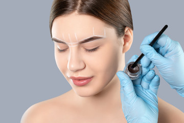 The make-up artist applies a henna paints eyebrow dye on the eyebrows of a young girl. Professional makeup and cosmetology skin care.