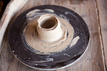 Potter's wheel with clay. Women's hands make a vase of clay.