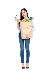 Full length of beautiful Asian woman with credit card holding paper shopping bag full of groceries isolated on studio white background