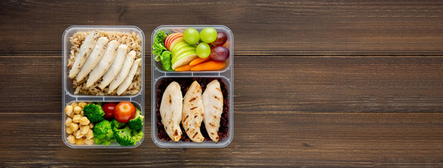 Clean healthy low fat food in two takeaway meal box sets on wood banner background top view with copy space