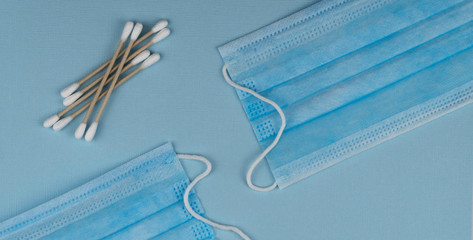 Flat lay composition with medical mask and natural cotton sticks on blue background.