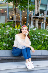 Portrait of beautiful sexy slim Asian woman sitting on step in the garden