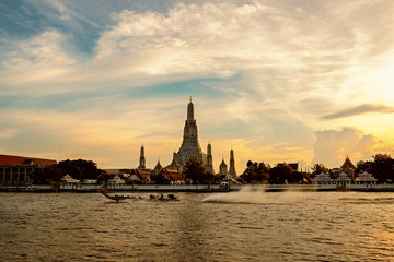 boat sailing in the middle of the Chao Phraya River and Wat Arun, Bangkok