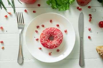 A delicious donut lies on a plate and eats to eat it. Problems of proper nutrition and the concept of choosing between wholesome and not wholesome food