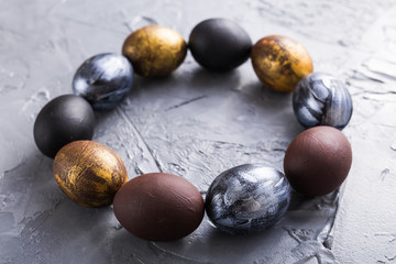 Holidays, traditions and Easter concept - Dark stylish easter eggs on grey background.
