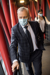 businessman in formal wear with medical mask looking away