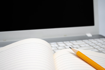 Online learning concept. There are a lined notebook and a yellow pencil on the keyboard of the laptop.