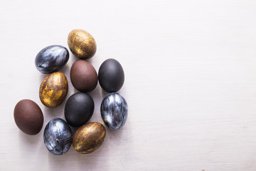 Holidays, traditions and Easter concept - Dark stylish easter eggs on white wooden background with copyspace.