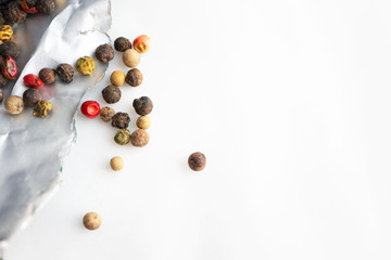 Black, red, white and green pepper. Peppercorn dry spice on white background, top view.