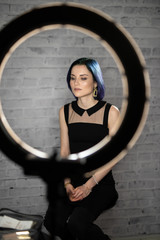 Girl sitting in front of a ring light in a beauty salon. Makeup artist, hair stylist space.