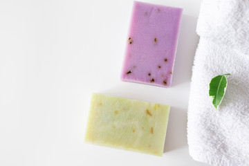 Hand made soap bars and green leaf on bath towel and on white background with copy space, top view. Concept health and body care spa, hygiene. Organic natural cosmetic