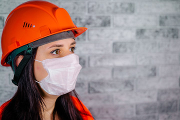 Portrait of young woman in medical mask on her face on background of gray brick wall. Adult female covered her face with mask to protect yourself from diseases