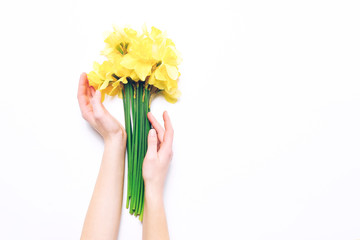 Spring narcissus flowers in female hands on white background.