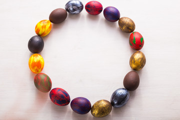 Multi-colored wooden letters making up the words happy easter and decorative colourful eggs on a white background with copy space.