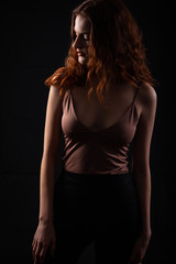 Portrait of a young curly girl in a dark studio