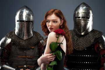 Beautiful girl in a black dress and knights in armor