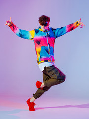 Guy dancing contemporary dance in studio. Neon light grey background. Acrobatic bboy dancer. Break...