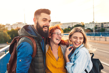 Group of tourists enjoying on vacation, young friends having fun walking on city street during sunset.