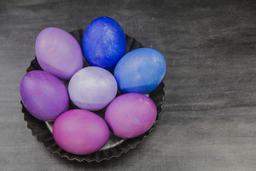 Blue and purple Easter eggs in a tray on a grey background