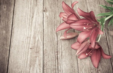 Lily flowers on old wooden table. Vintage floral background. Toned image in retro style. Copy space