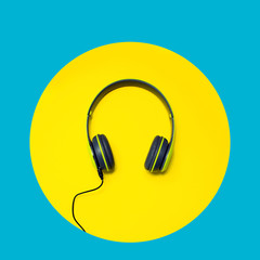 Modern headphones on a bright blue background with a yellow circle. Music lover concept