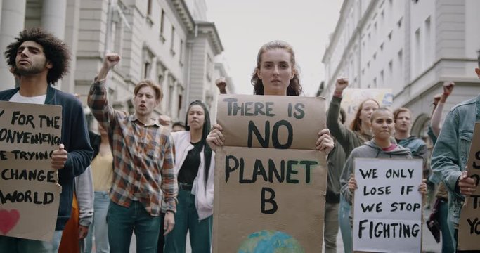 Young woman holding poster with There is no planet B. Group of protestors making a protest about global warming and plastic pollution.
