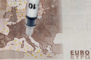 Syringe needles in a map of Europe on paper money. The spread of the virus, disease, epidemic. Search for a vaccine and treatment.