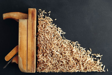 Old hand plane and wood shavings on black background. Old woodworking hand too on a black background. Copy, empty space for text