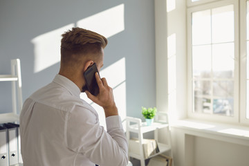 Fototapeta premium Formal male speaking on smartphone in sunny office