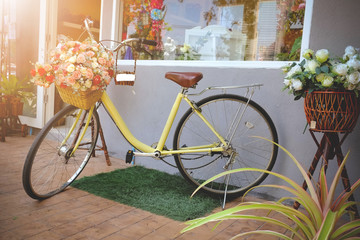 Fototapeta na wymiar vintage Bicycle with basket full rose flower next to a modern cafe