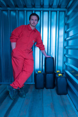 Fototapeta na wymiar Young worker in red working suit working with petrol cans in a container