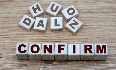 concept of the word CONFIRM on cubes on a light wooden background