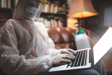 Woman with protective antiviral mask and uniform using laptop at home, working, reading news, surfing the internet, ordering food online.