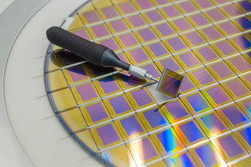 Silicon wafer with microchips, fixed in a holder with a steel frame on a gray background after the...