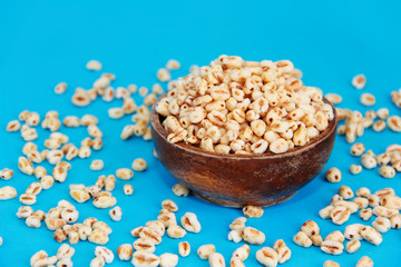 grains of edible puffed rice in a decorative plate on a blue background