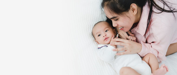 Asian mother playing with her baby on the bed the baby smile and laugh with happy and funny. Motherhood, mom and kids, healthy of children, family relationship concept.