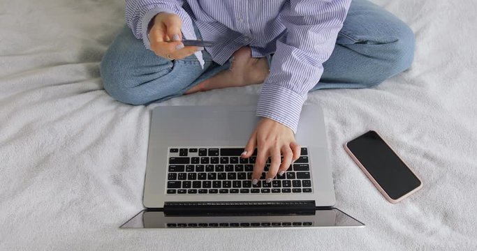 Top view of Female Woman hand holding a black platinum metal credit card and shopping online. Girl with laptop and bank card stay at home and ordering clothes. Easy pay using digital gadget concept.