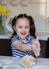 Easter concept. happy cute child girl is are preparing the Easter cakes, bake cookies in the kitchen. Portrait of happy funny kid in the Easter