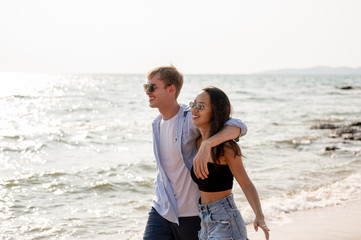 Fototapeta na wymiar Couple caucasian and latin are walk together at the beach with sunset. Summer vacation relaxation, travel, nature, happy life unseen concept.
