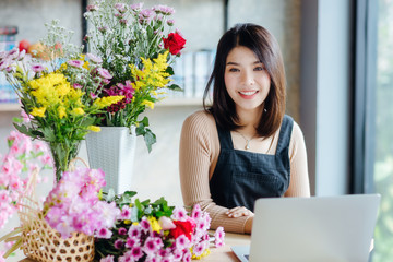 Beautiful Asian woman receive orders from internet in flower shop.