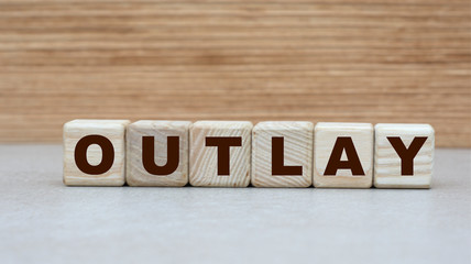 concept of the word OUTLAY on cubes on a wooden background