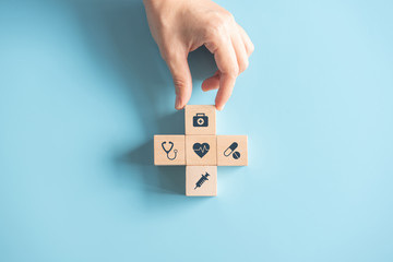 Health medical Insurance Concept, Hand arranging wood cube with medical symbol on pastel blue background, copy space. - obrazy, fototapety, plakaty