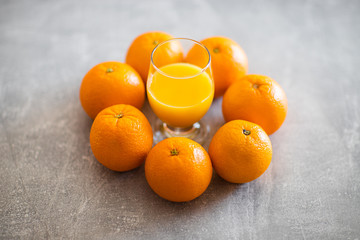 Sok pomarańczowy w szkle, dookoła świeże pomarańcze