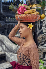 Asian girl. Beautiful Balinese women in traditional dress with yellow plumeria frangipani flower makes offering for Gods near the temple. Balinese tradition.