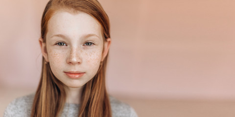 Close up portrait of young expressive emotional ginger girl with freckles on her face looking at...