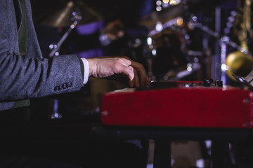 Fototapeta na wymiar Concert view of a musical keyboard piano player during musical jazz band orchestra performing, keyboardist hands during concert, male pianist on the stage