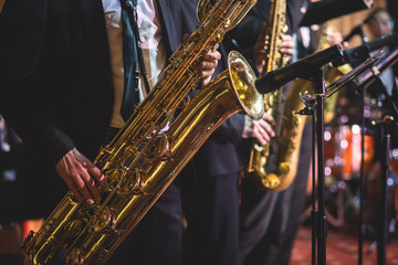 Concert view of a saxophonist, saxophone player with vocalist and musical during jazz band orchestra performing music on stage