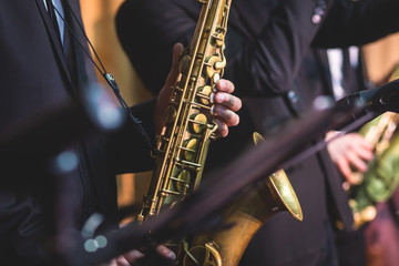 Concert view of a saxophonist, saxophone player with vocalist and musical during jazz band orchestra performing music on stage