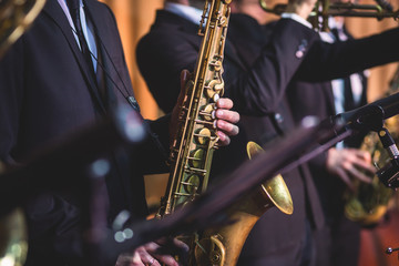 Fototapeta premium Concert view of a saxophonist, saxophone player with vocalist and musical during jazz band orchestra performing music on stage
